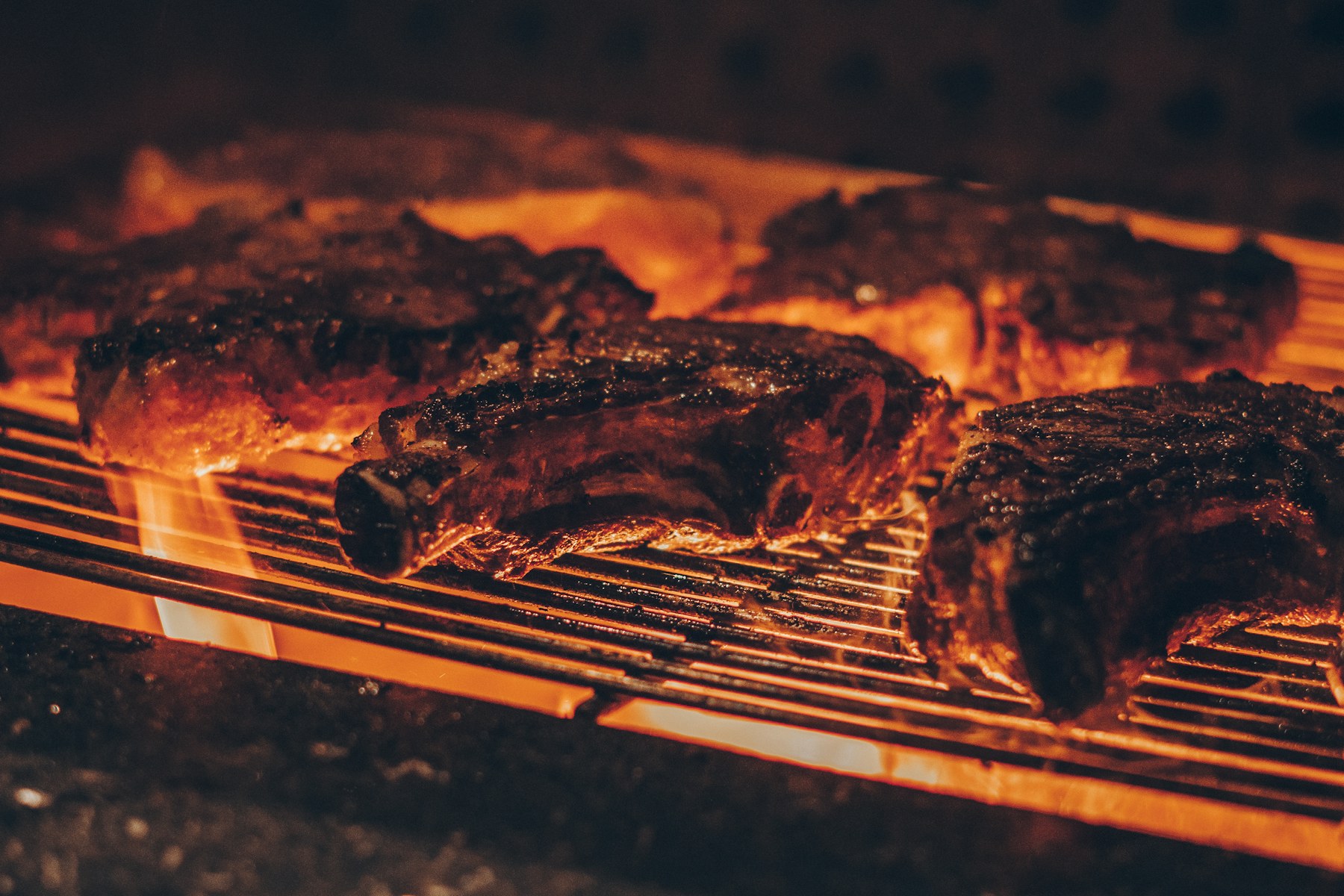 Steaks cooking over a hot open-flame grill